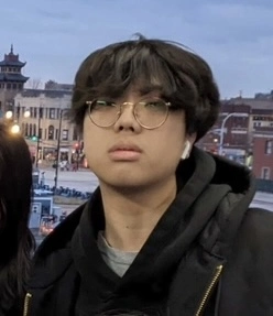 A picture of Caleb, wearing glasses and a jacket